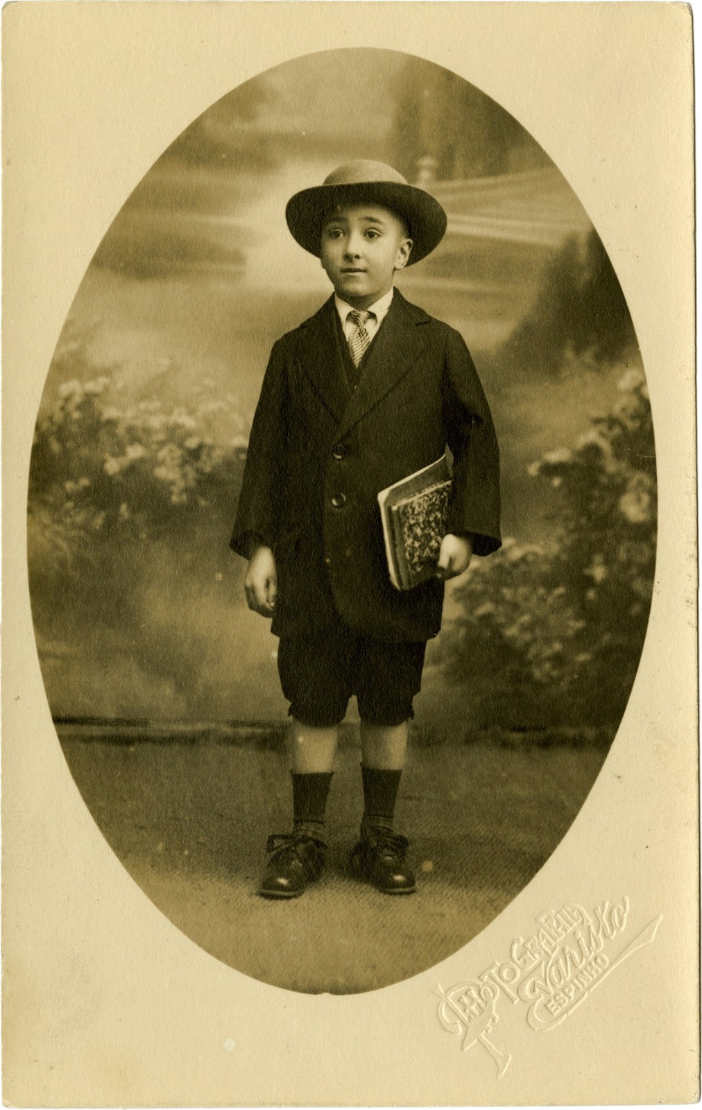 Soeiro Pereira Gomes com 7 anos, de fato e chapéu e com cadernos debaixo do braço, por Photograph...